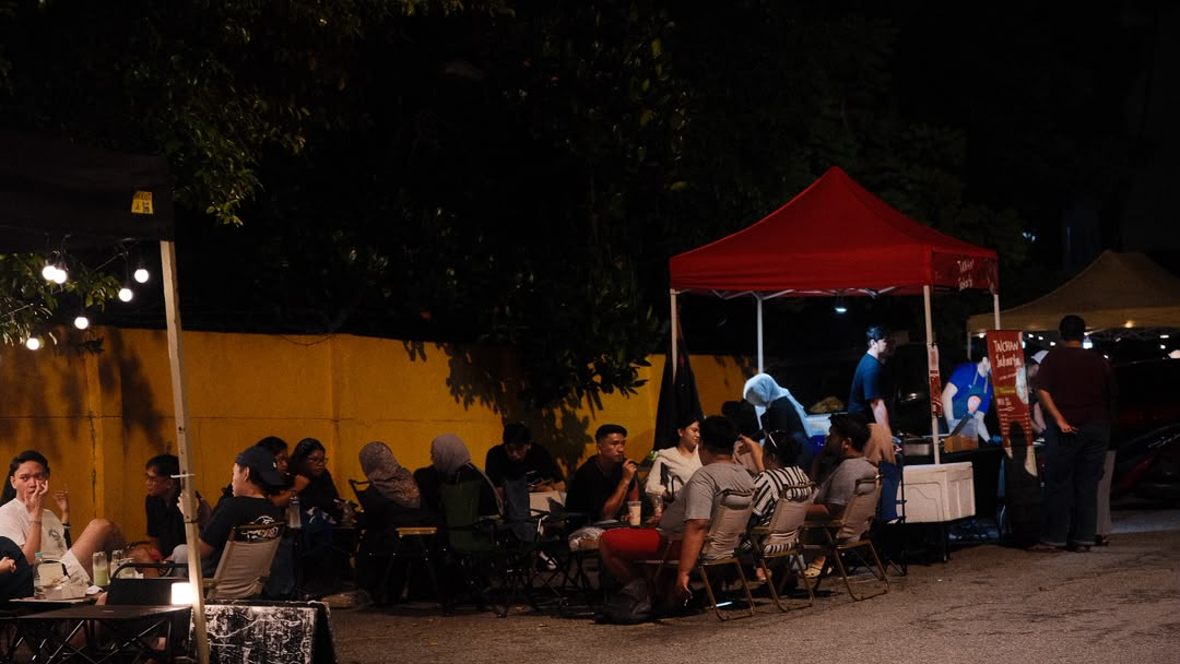 Taichan Jakarta catering setup at a night event — red tent stall with crowd seated nearby.